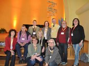 Gruppenfoto von zehn Personen, die vor einer orangefarbenen Wand stehen